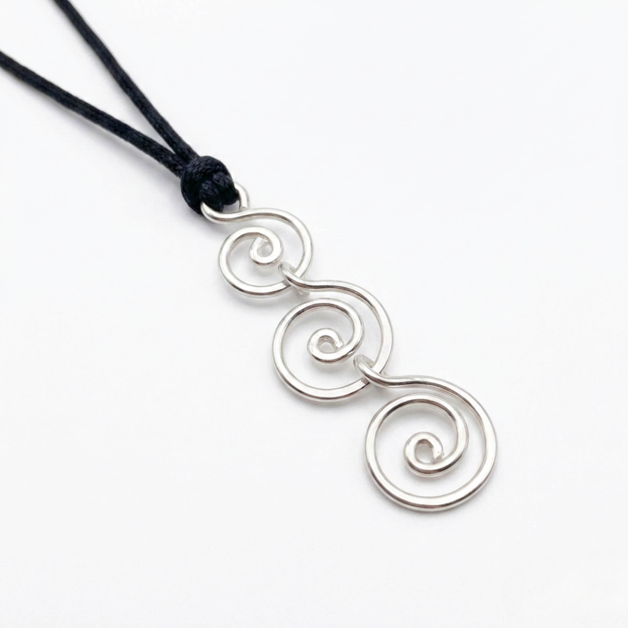 Silver spiral pendant on a black cord against a white background