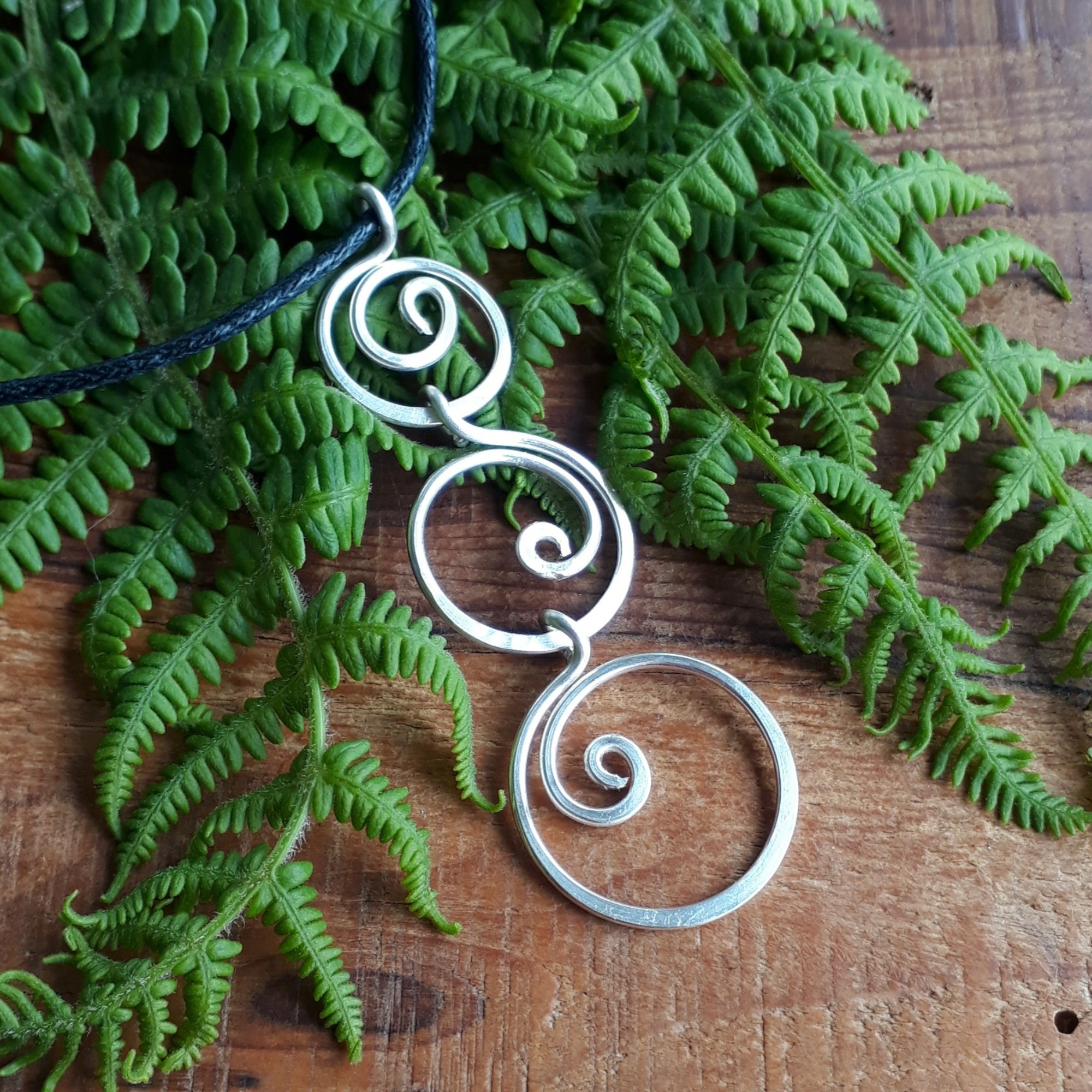 3 ascending spirals on a black cord pendant