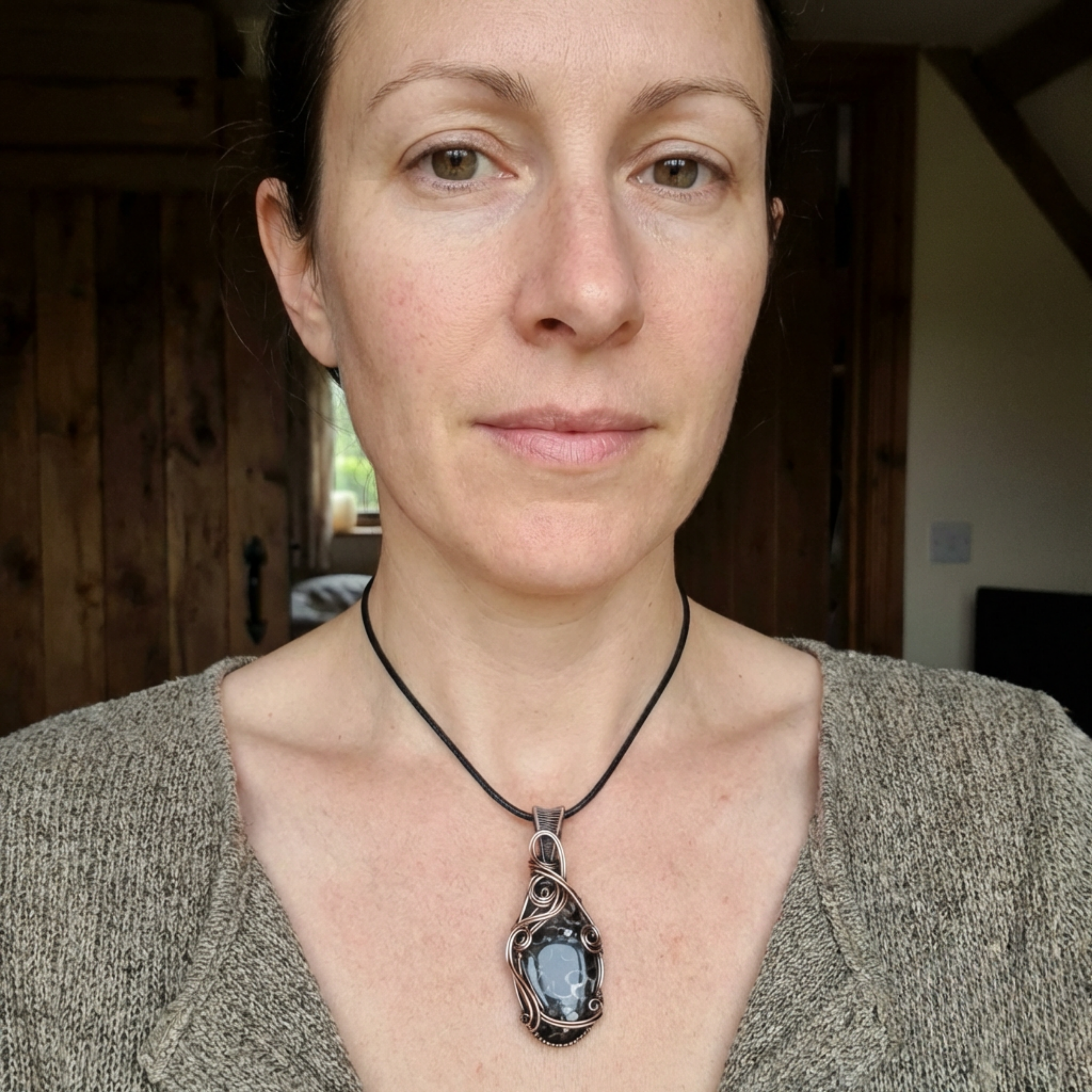 Woman wearing a necklace with a Turritella agate gemstone pendant indoors