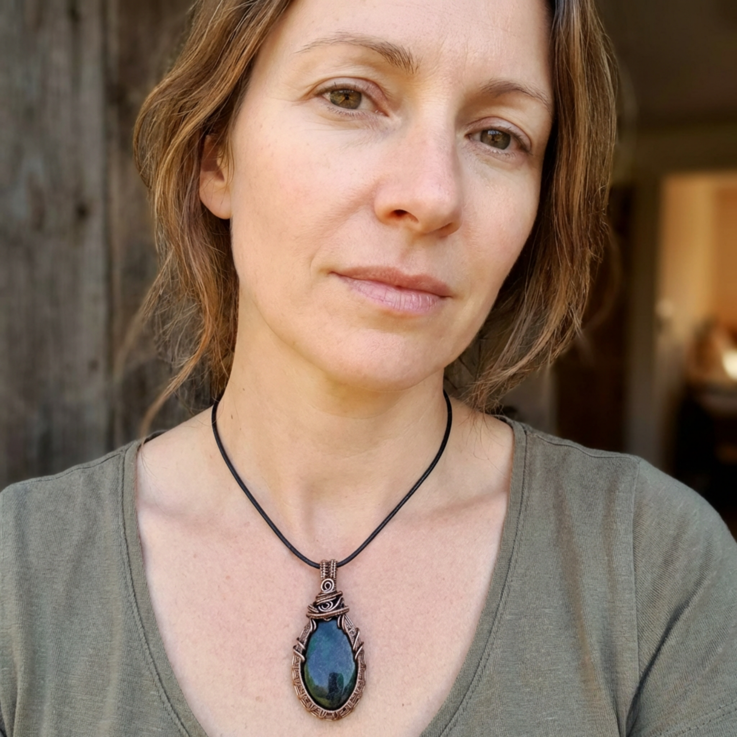 Woman wearing a necklace with a blue pendant against a blurred background