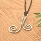 Gold spiral necklace on a wooden surface with a plant leaf
