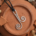 Silver wire-wrapped pendant on a black cord against a rustic brown background