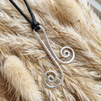 Silver wire-wrapped pendant on a black cord against a fur background