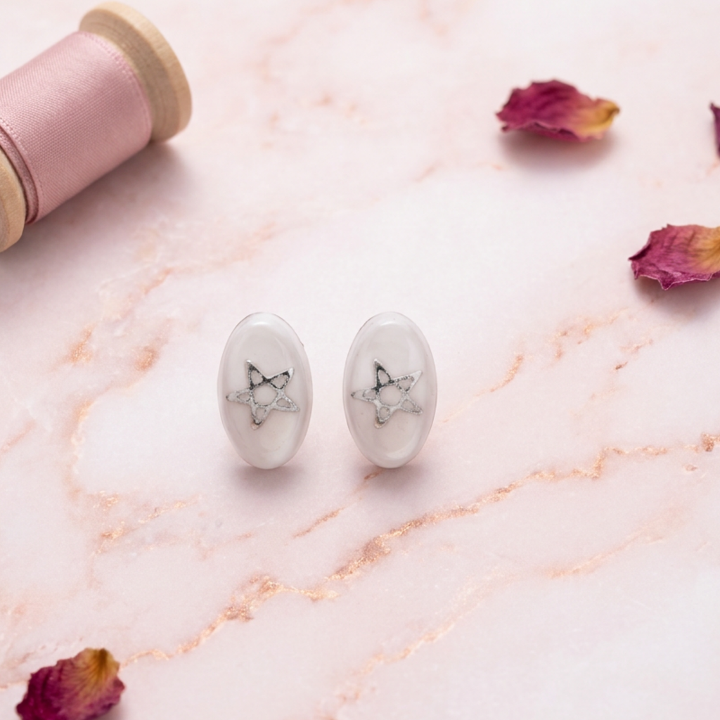 White stud earrings with stars on a decorative surface