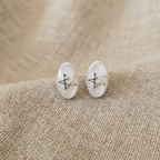 White and clear stud earrings with silver stars on a fabric surface