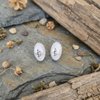 Pair of earrings with star design on a stone surface with natural elements