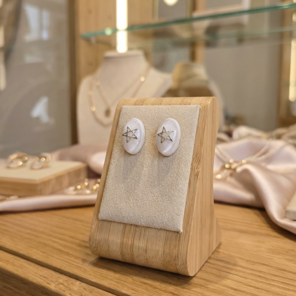Pair of earrings on a wooden display stand with a blurred jewelry store background.