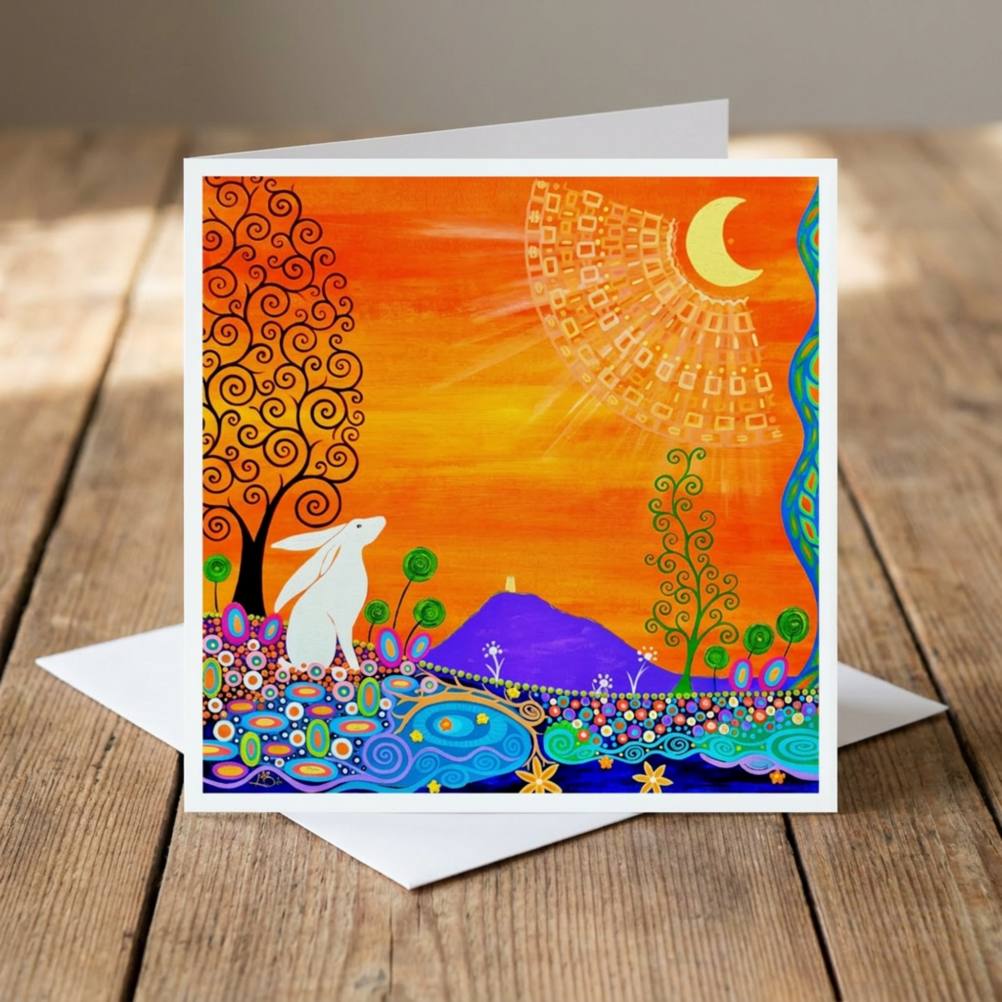 Colourful greeting card with artistic hare and glastonbury Tor design on a wooden surface