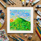 Colourful abstract painting of Glastonbury Tor on a wooden surface with art supplies