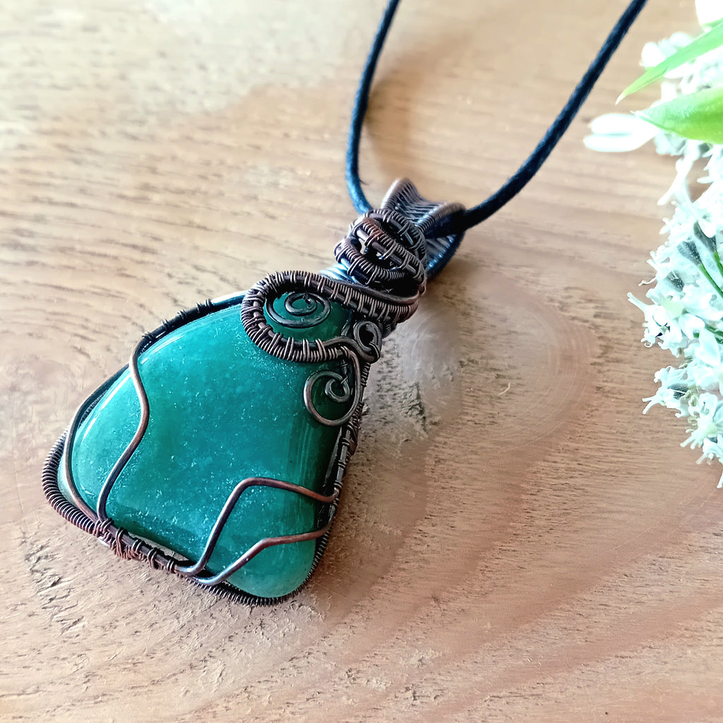 Green Aquamarine stone pendant with wire wrapping on a wooden surface