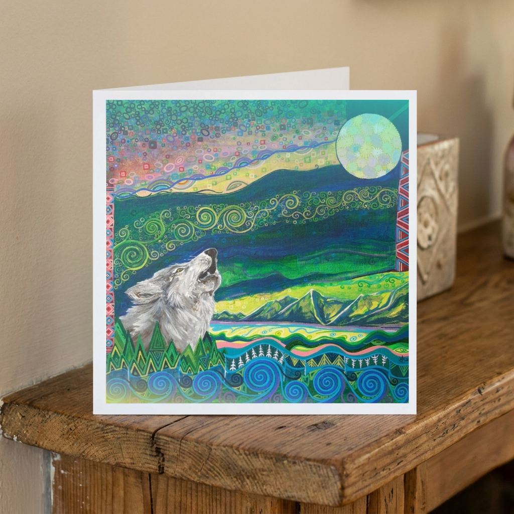 Greeting card with a wolf howling at the moon design on a wooden surface.