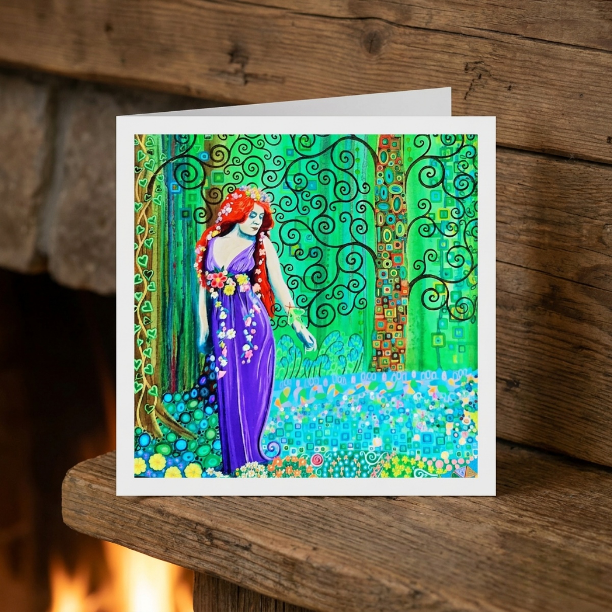 Colourful greeting card with artistic design of a woman in a purple dress against a stylized tree and landscape on a wooden surface.