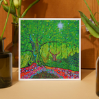 Colorful abstract artwork with a deer in a forest setting, framed and displayed on a wooden surface.