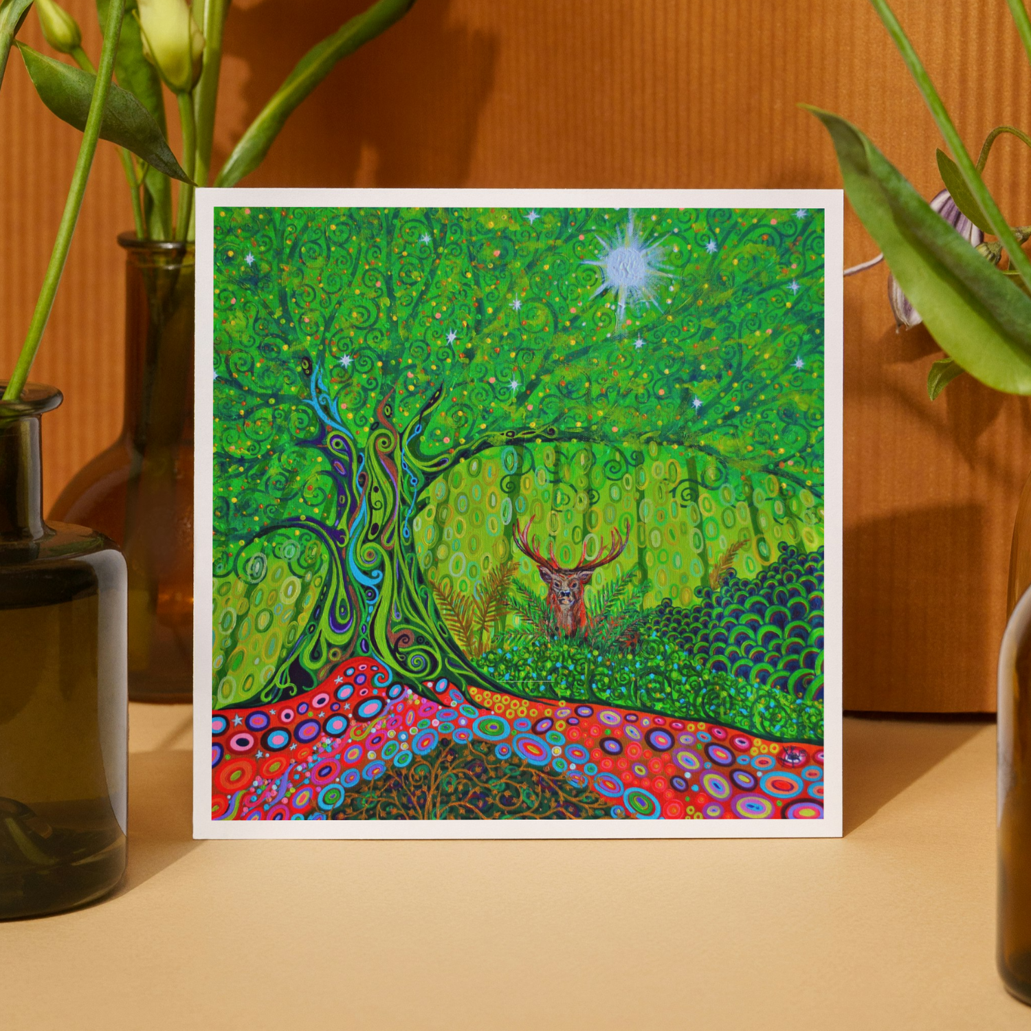 Colorful abstract artwork with a deer in a forest setting, framed and displayed on a wooden surface.