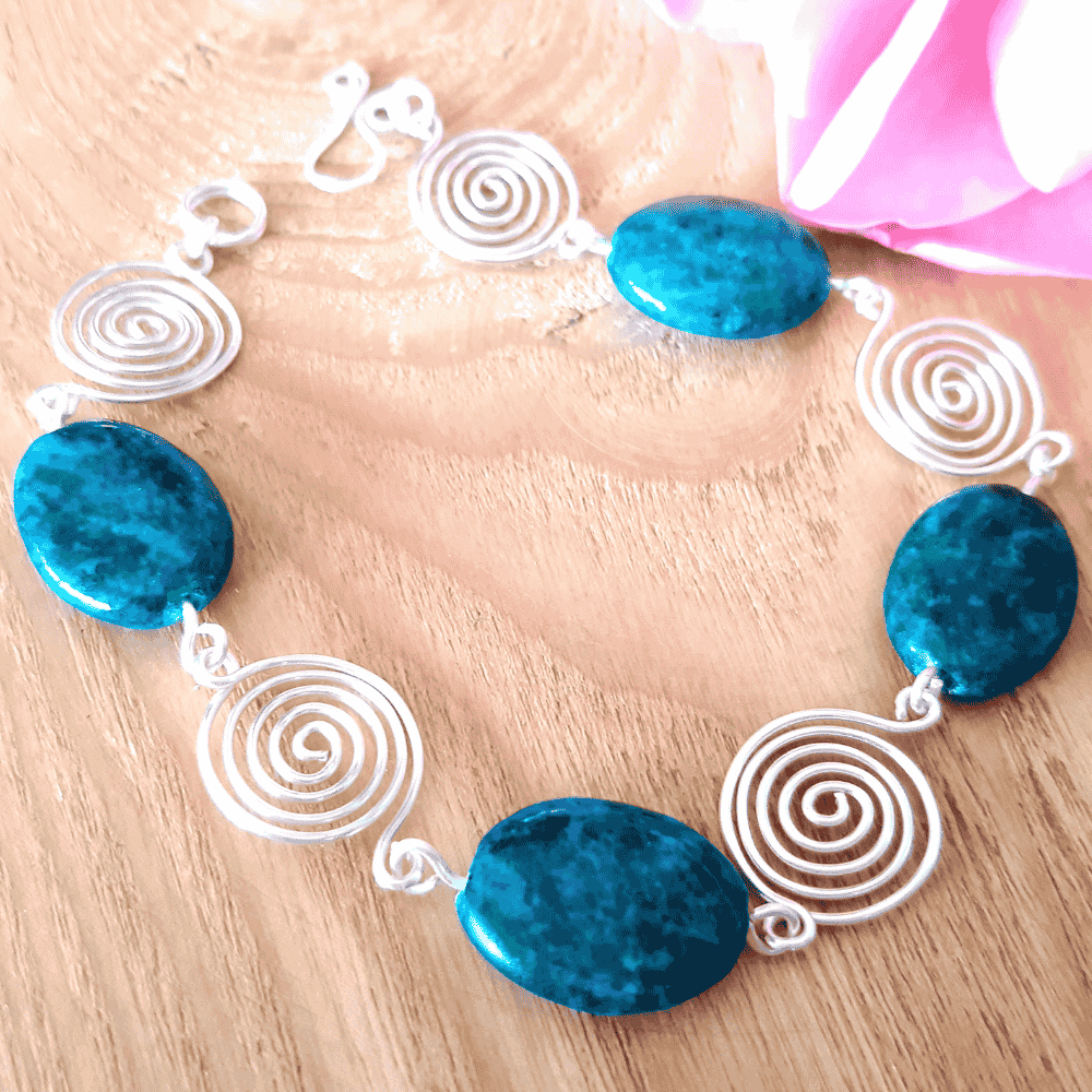Bracelet with blue beads and silver spiral designs on a wooden surface