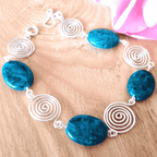 Bracelet with blue beads and silver spiral designs on a wooden surface