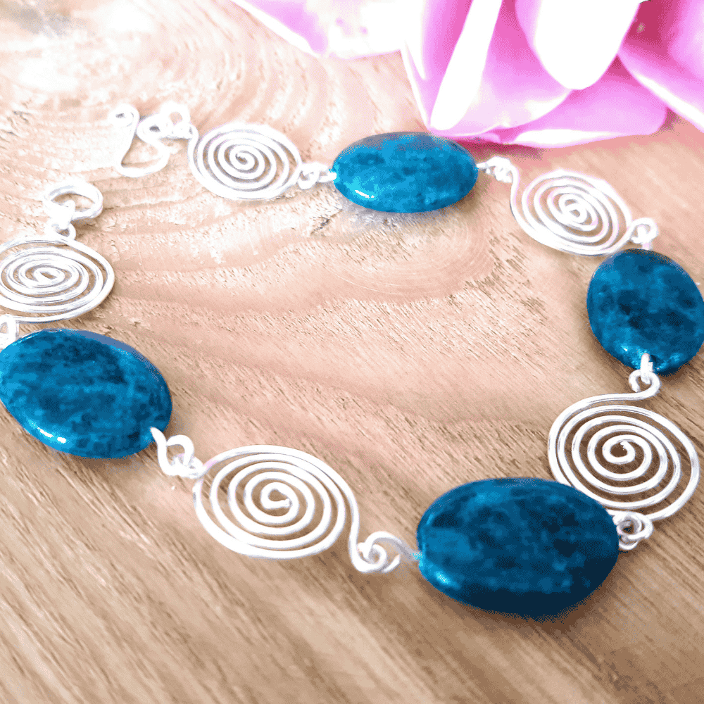 Bracelet with blue beads and white spiral designs on a wooden surface