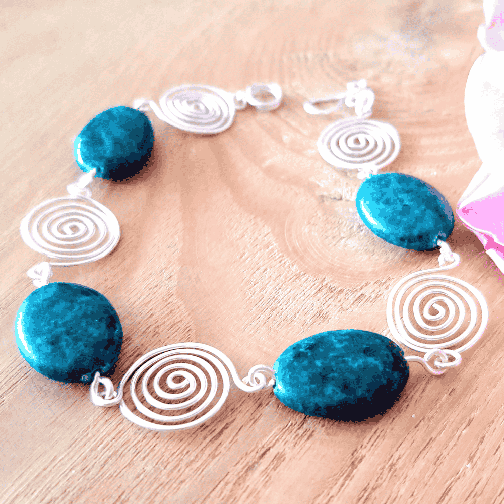 Bracelet with blue Azurite beads and white spiral designs on a wooden surface