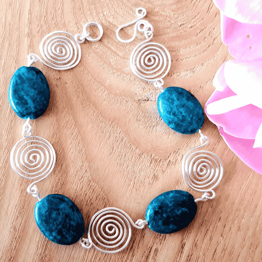 Bracelet with blue stones and open silver spiral designs on a wooden surface