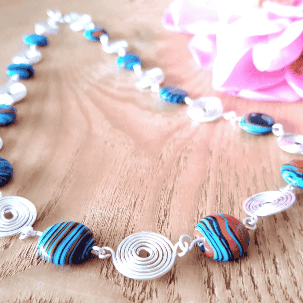 Necklace with colorful beads and silver spirals on a wooden surface