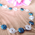 Necklace with blue and silver spiral beads on a wooden surface
