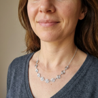 Woman wearing a silver necklace against a neutral background