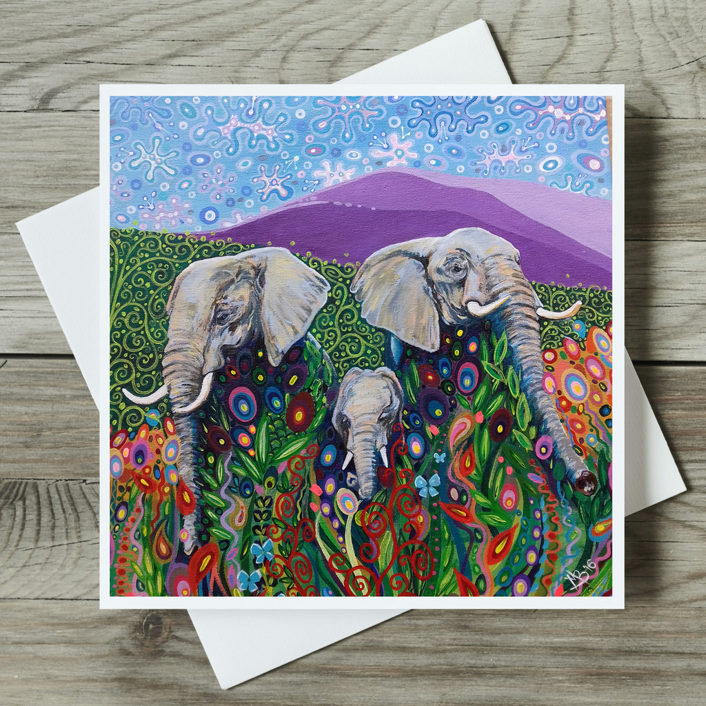 Colorful card with elephants and floral patterns on a wooden surface