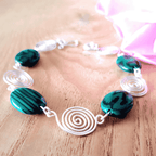 Bracelet with green beads and white spiral designs on a wooden surface