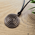 Copper spiral pendant on a wooden surface