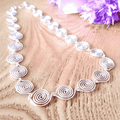 Tear drop shaped spiral form a chain to make this silver spiral necklace on a wooden brackground with purple flowers