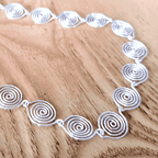 Silver spiral necklace on a wooden surface
