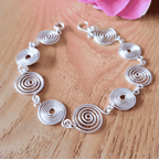 Open silver spiral bracelet worn by model, handmade wire jewellery UK