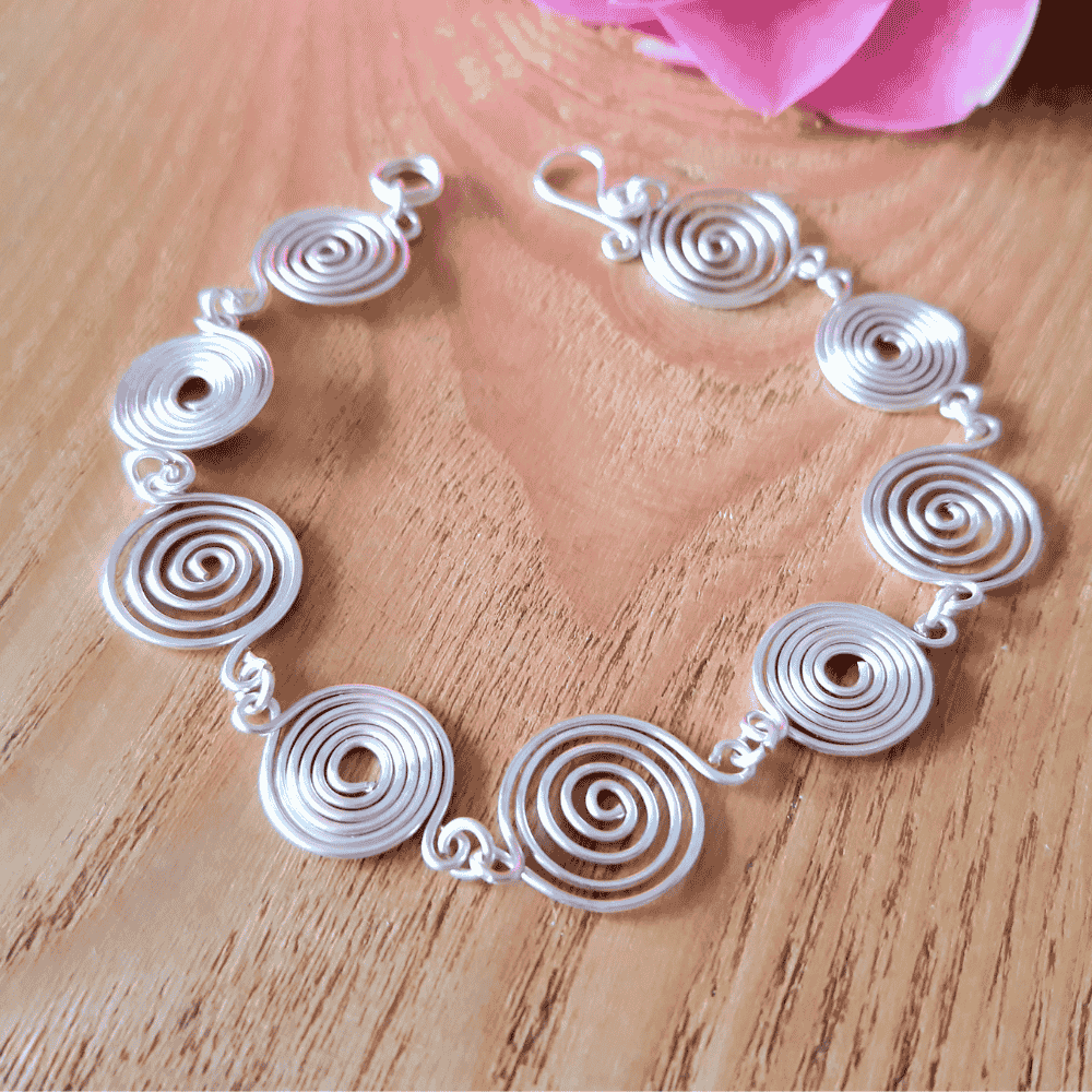 Open silver spiral bracelet worn by model, handmade wire jewellery UK