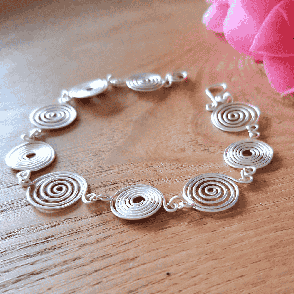 Open silver spiral bracelet flat lay, handmade wire jewellery UK, Wildform