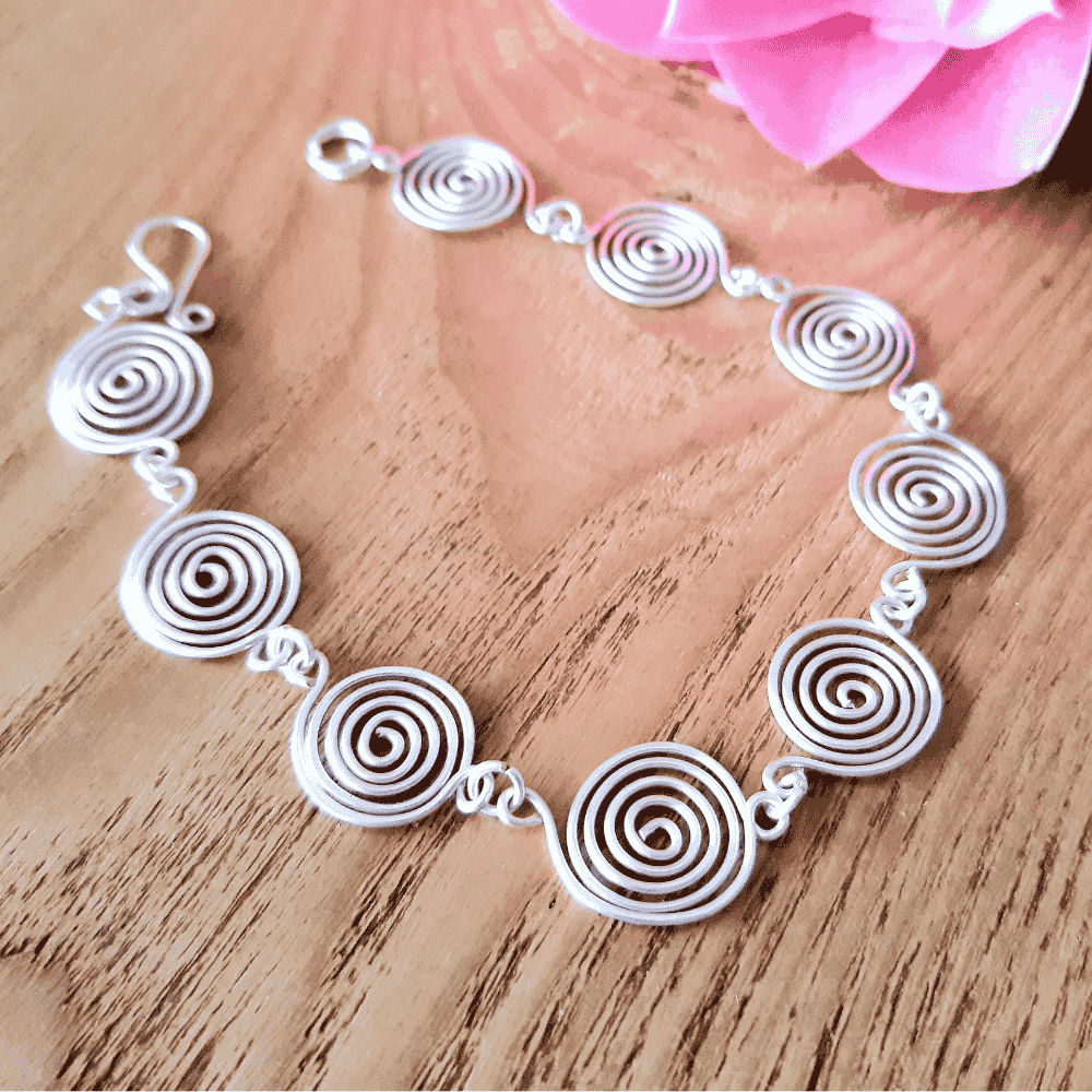 Open silver spiral bracelet worn by model, handmade wire jewellery UK
