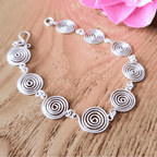 Open silver spiral bracelet worn by model, handmade wire jewellery UK