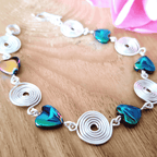 Bracelet with heart-shaped beads and silver spirals on a wooden surface
