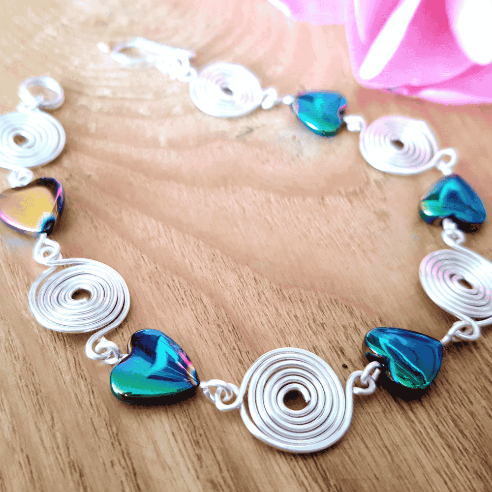 Bracelet with heart-shaped beads and silver spirals on a wooden surface