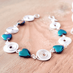 Bracelet with silver loops and blue heart-shaped beads on a wooden surface