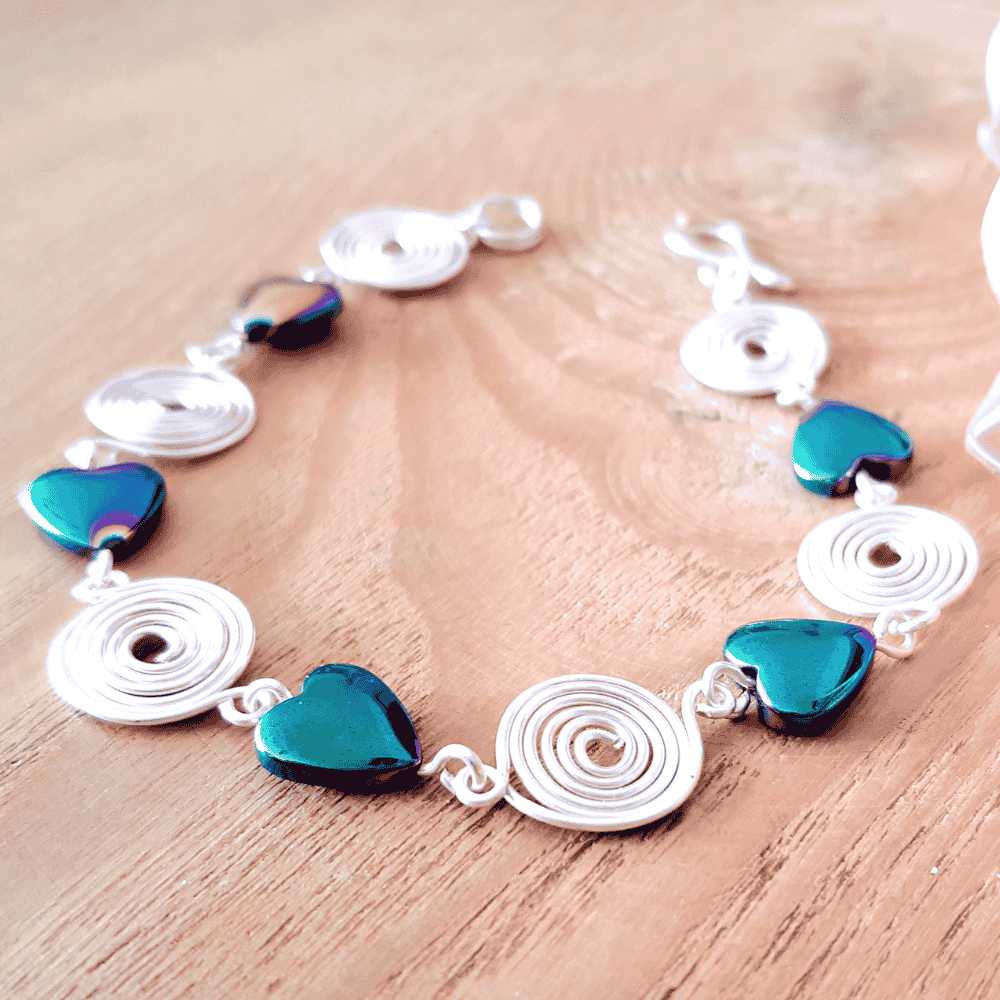 Bracelet with silver loops and blue heart-shaped beads on a wooden surface