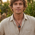 Man wearing a beige shirt and necklace with a natural background